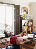 Ein Kinderzimmer mit diversen Stofftieren und ein Schaukelpferd vor dem Fenster
