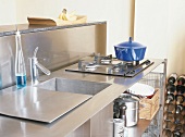Edelstahl-Küchenelement mit bedeckbarem Spülbecken und einem direkt daneben angebrachten Gasherd