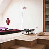 Raum im asiatischen Stil, mit Holzdielen, Bodenkissen, Teetisch und Futonmatratze