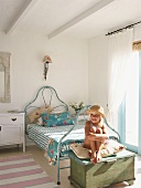 Little girl sitting on trunk in bedroom