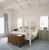 Holzkommode am Bettende eines Himmelbettes im Schlafzimmer