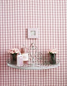 Ein kleines Regal an rosa-weiss-karierter Wand