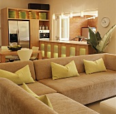 L-förmiges Sofa mit grünen Kissen vor Einbauhüche mit Durchreiche zu einer Loggia