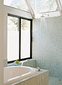 Offene Dusche und Badewanne mit blauen Mosaikfliesen und verglaster Dachkonstruktion