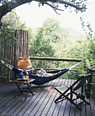 Mann in einer Hängematte auf Holzterrasse mit Ausblick auf grüne Landschaft