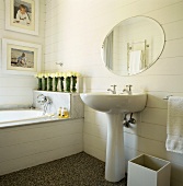 Badezimmer mit freistehendem Waschbecken und rundem Wandspiegel neben Badewanne