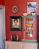 Small cabinet of spices, toaster & African painting in kitchen