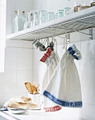 Tea towels hanging from kitchen shelf
