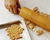 Crushing sesame brittle in plastic bag with rolling pin