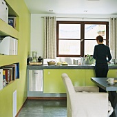 Frau beim Abwasch in Küche mit grünen Schrankfronten