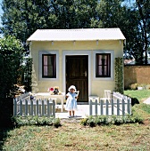 Little girl in front of shed with picket fence