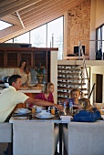 Family eating meal in open-plan interior with kitchen and mezzanine