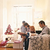 Familie blättert in Büchern im Wohnzimmer zu Weihnachten