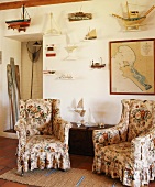 Maritim dekorierte Sitzecke mit zwei floral gemusterten Ohrensesseln und alter Holztruhe