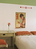 Schlichter, aber liebevoll dekorierter Schlafraum in Grün- und Rottönen mit japanischem Werbeplakat