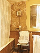 Altes Badezimmer in warmem Licht mit Holzvertäfelung und teilweise abgebröckeltem Wandputz