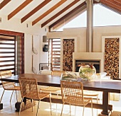 Großer Esstisch und Kamin in einem Raum mit schräger Holzbalkendecke und verglastem Giebel