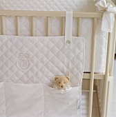Die weiße Betttasche aus gestepptem Stoff schafft Ordnung an und im Kinderbettchen