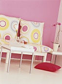 Durch die schlichten Möbel und eine rosa Wand mit abgestimmten Wohnaccessoires entsteht ein modernes Retrogefühl