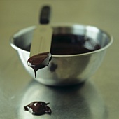 Flüssige Schokolade in Metallschüssel und auf Messer