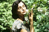 Woman smelling branch of fragrant blossom