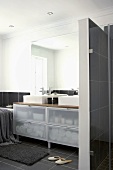 Ein Waschtisch mit transparenten Schubladen in einem modernen, schwarz gefliesten Badezimmer