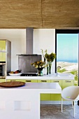 Eine moderne Küche mit grünen Fronten und ein Designertisch unter einer Rohbetondecke