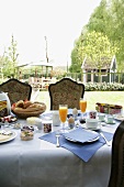 Ein reich gedeckter Frühstückstisch auf der Terrasse mit Blick auf den großen Garten