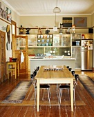 Esstisch und Küchenstühle in einer offenen, bunt dekorierten Wohnküche mit altem Dielenboden