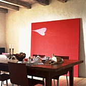 Rustikaler Frühstückstisch vor einem großen, an der Wand lehnenden Gemälde in Rot