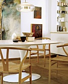 Verschiedene Schalen auf einem 60er Jahre Esstisch mit schlichten Holzstühlen vor einer Gemäldewand
