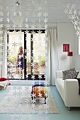 Blick durch floralen Fadenvorhang in modernes Wohnzimmer mit Terrassenzugang und türkisfarbenem Fußboden