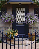 Klassisch elegante Eingangstür im englischen Stil, eingefasst von zwei Blumenbüschen
