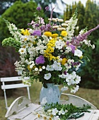 Colourful arrangement of summer flowers on garden table out of doors