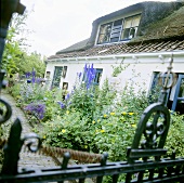 Reetgedecktes Haus mit üppig blühendem Ziergarten und einem ziegelgepflasterten Weg