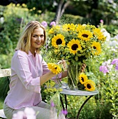 Young woman putting sunflowers in vase