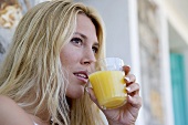 Blond woman drinking a glass of orange juice