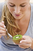 Woman eating a kiwi fruit