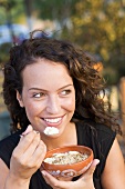 A woman eating yoghurt with honey and grated nuts