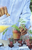 Man adding pineapple juice to a melon cocktail