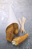 Three deep-fried fish nuggets in a greaseproof paper cone