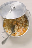 A pan of pumpkin risotto with spoon and propped lid
