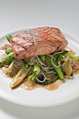 A fried salmon fillet on mie noodles and vegetables