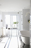 Freistehende Badewanne mit silbernen Füssen in lichtdurchflutetem Badezimmer