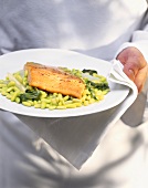 Chef holding plate of salmon fillet on soya beans