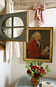 A corner of a room with a painting and bunch of flowers