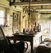 Ländlich, rustikaler Wohnraum in altem Ziegelhaus mit Kerzenbeleuchtung, Tisch, Schaukelstuhl & Strohballen als Sitzbank