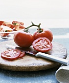 Vine tomatoes on chopping board with knife