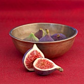 Fresh figs with a bowl on red fabric