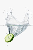 A slice of cucumber falling into water